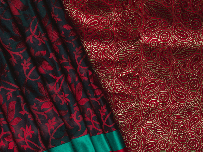 A close-up of a rich red textured fabric paired with a black pleated material featuring pink floral patterns.