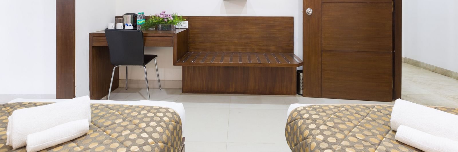 A room with twin beds, a work desk, a television, and a separate seating area - Sanctum Suites BEL Road, Bangalore