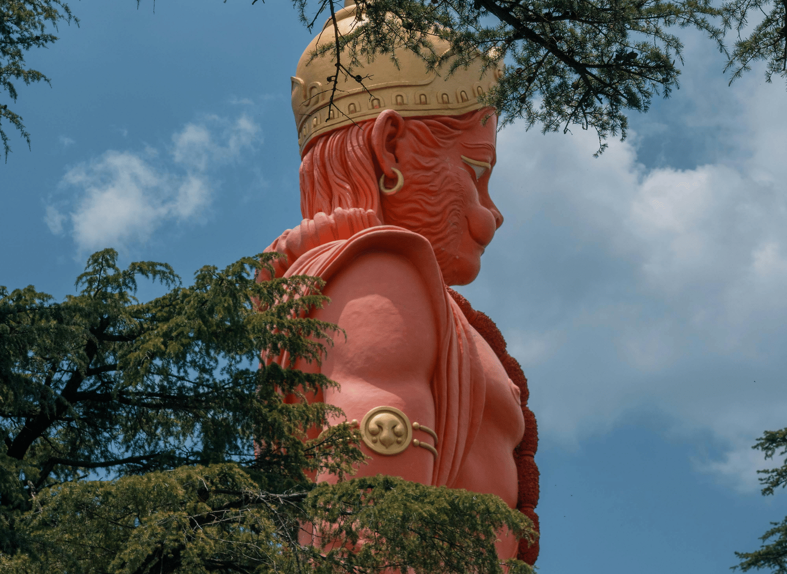 A tall Hanuman statue surrounded by trees.