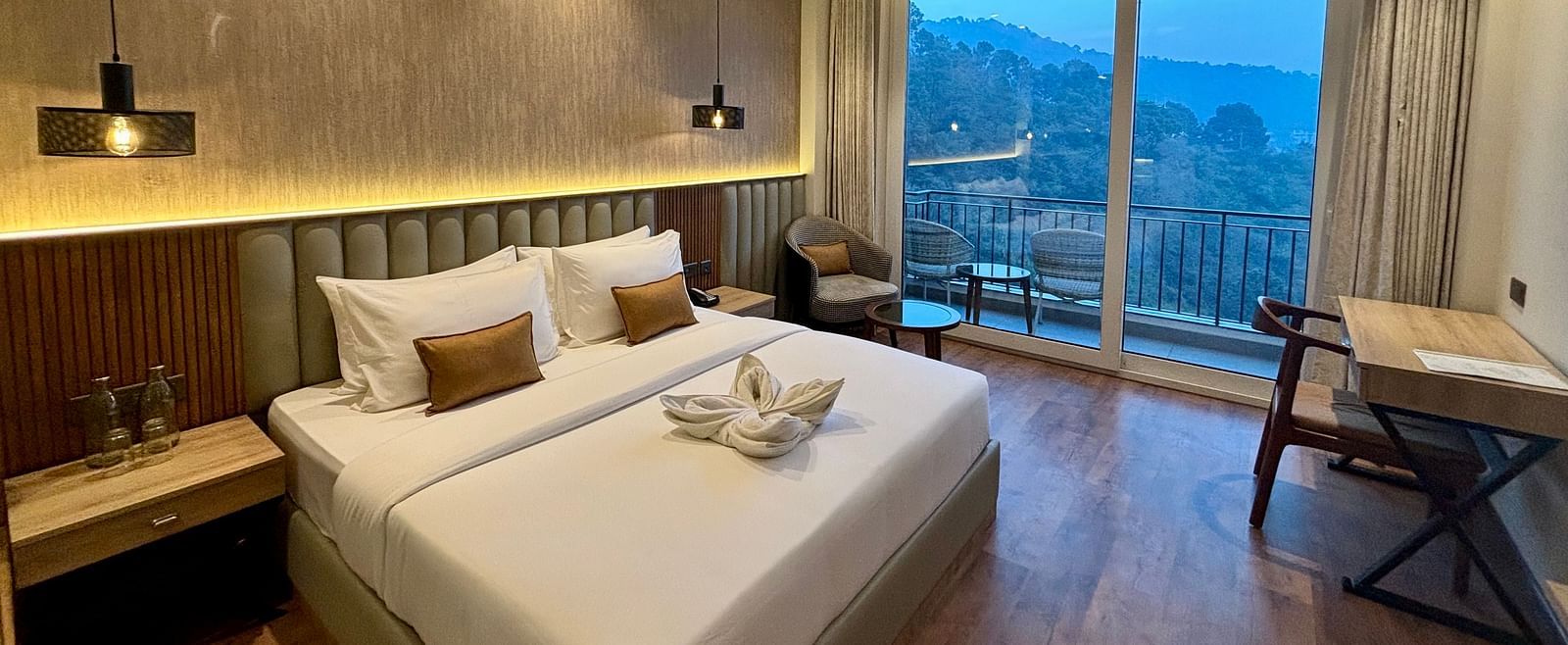 Cosy double bedroom with wooden flooring, ceiling fan, and balcony offering scenic views – ARNISA Boutique Hotel