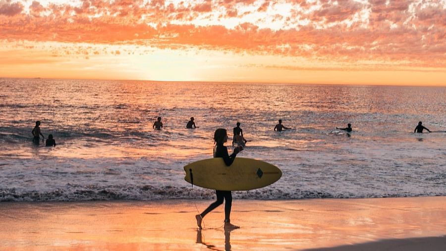 A girl walking with a surf board