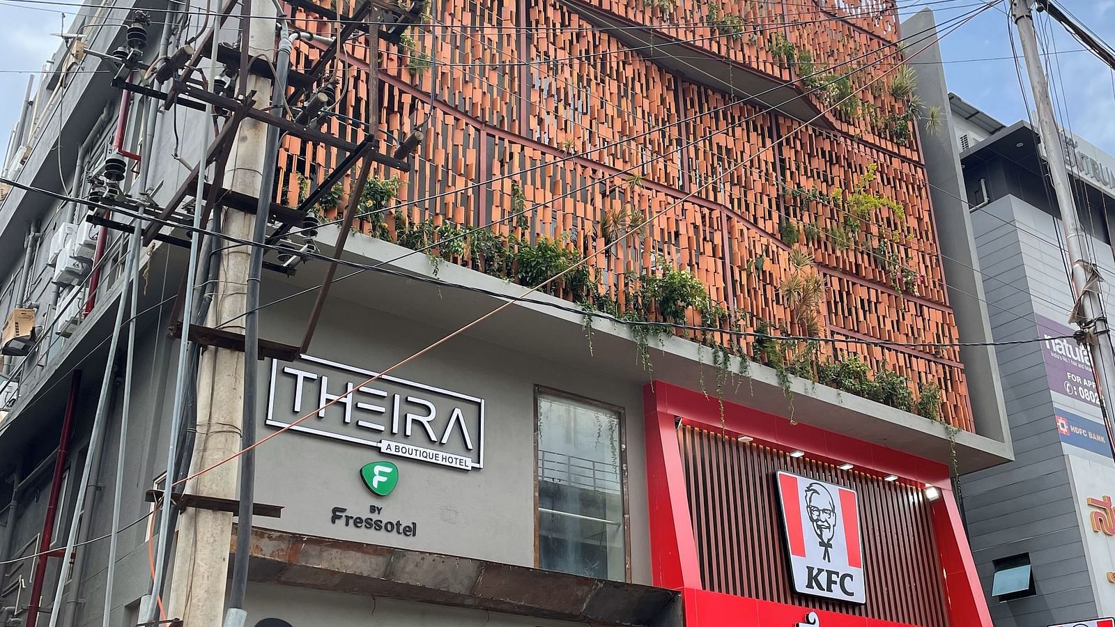 Facade image of Theira Fressotel, Bangalore with white clouds on blue sky in the background
