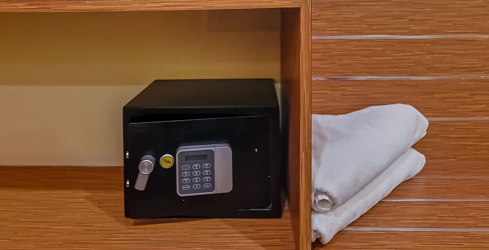 Shelf with water bottles, kettle, cups and digital safe at Max Hotel Prayagraj.