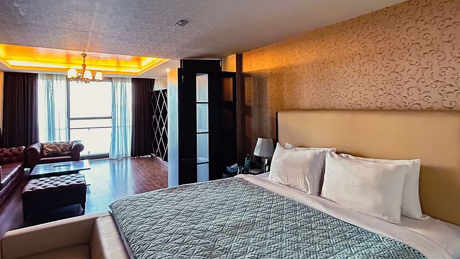 Comfortable bedroom with warm lighting, elegant bedding, and large windows at Aranya Himalayan Retreat