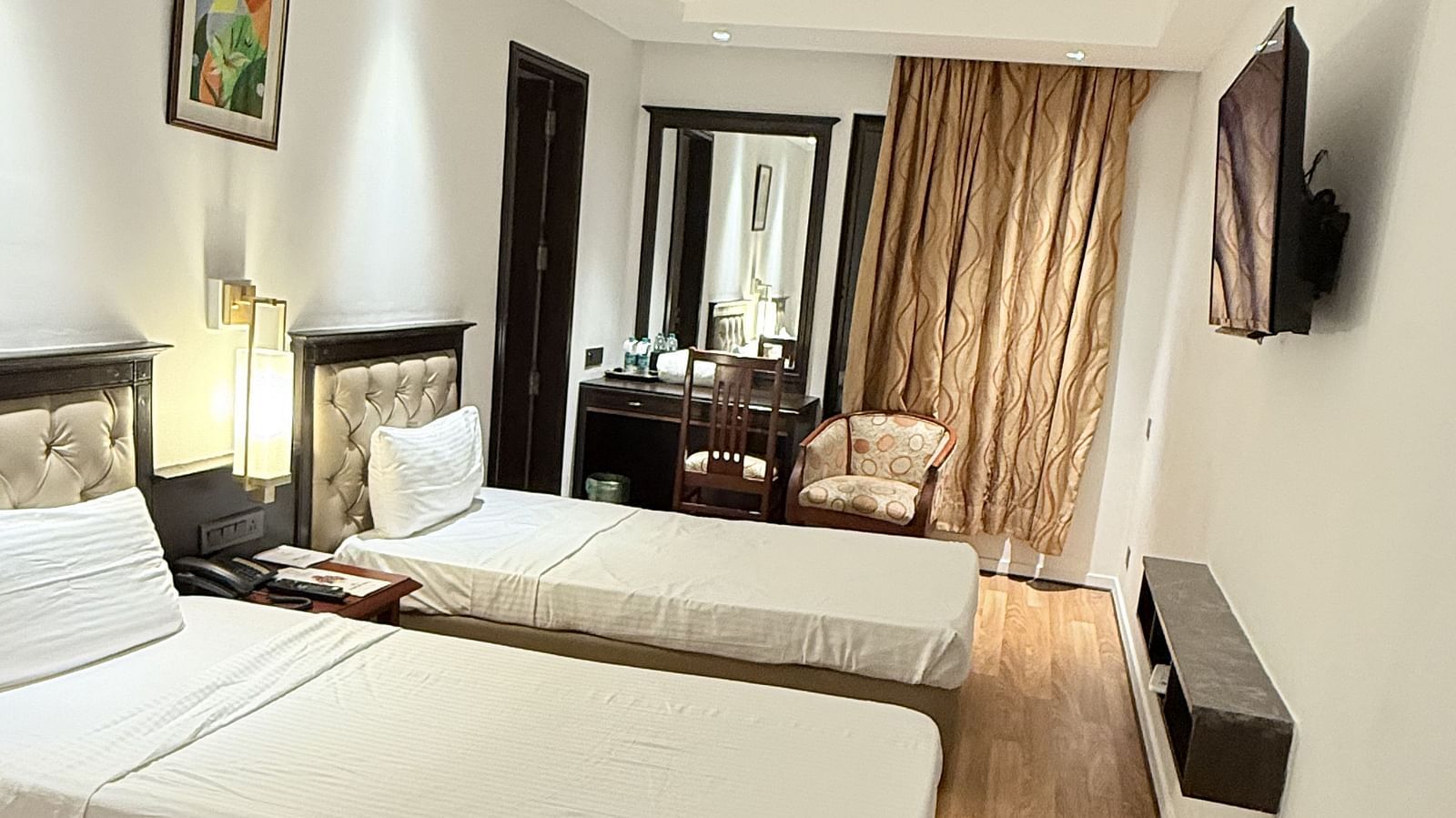 A spacious room with twin beds and a wall-mounted TV opposite them | Cenneys Gateway