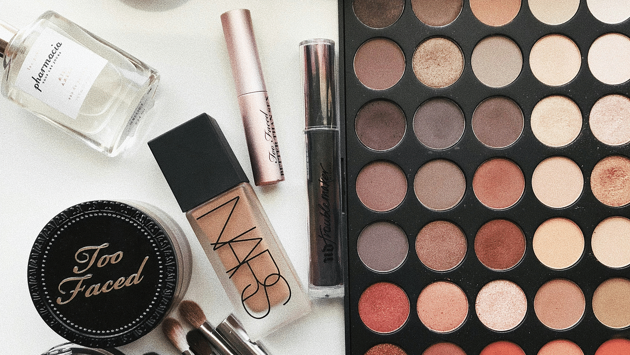 Beauty cosmetic products arranged on a table, featuring brushes and a vibrant color palette