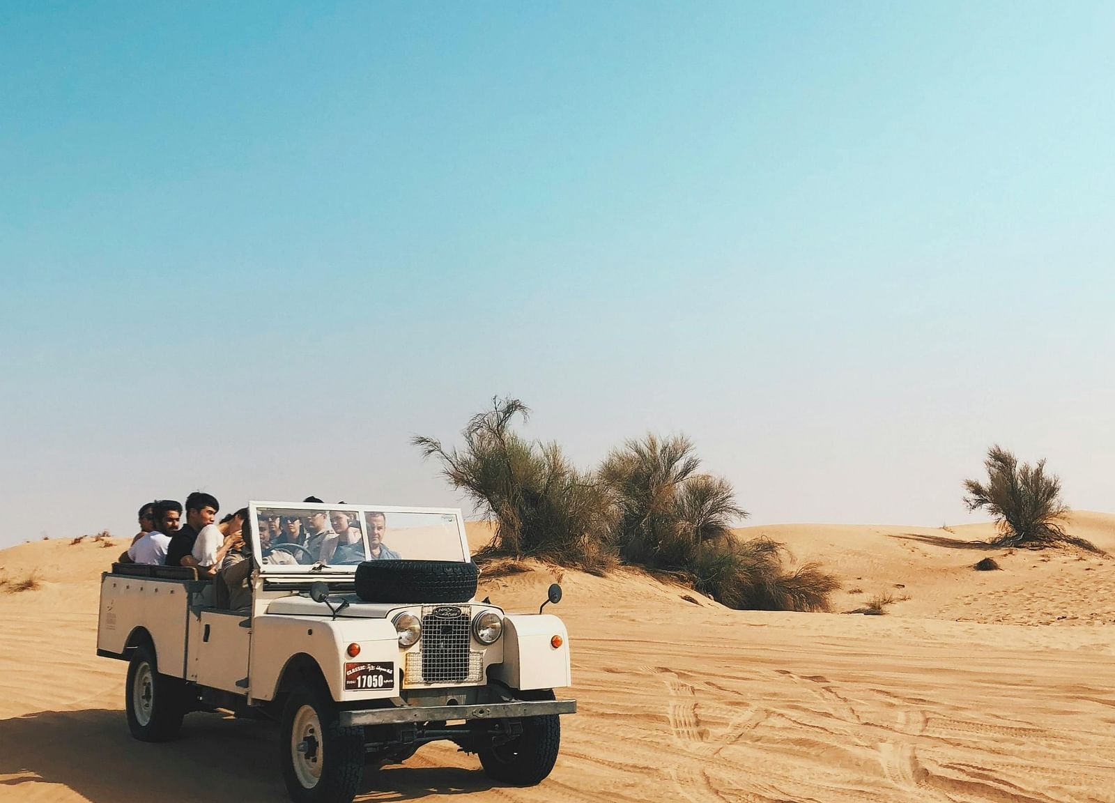 A jeep driving through a sandy desert landscape.