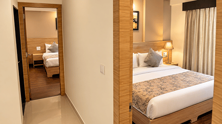 Deluxe Two Bedroom Suite at Starlit Suites, Shirdi, with a hallway leading to two bedrooms, one showing a bed with a patterned runner and grey cushions.