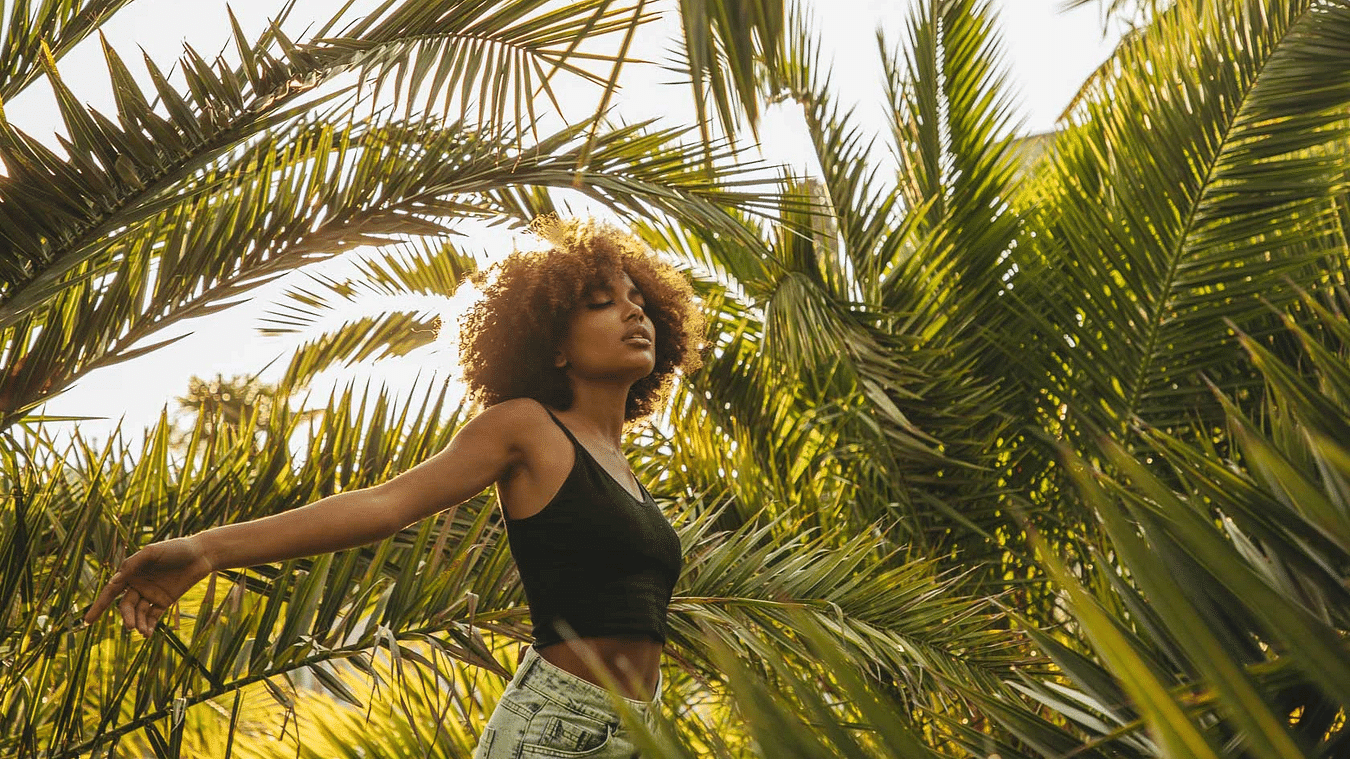 A woman walking among lush green palm trees - S Hotel Montego Bay, Jamaica