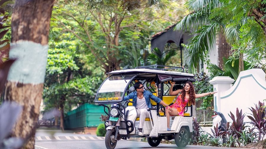 Couple enjoying a fun ride in a tuk-tuk surrounded by lush greenery and a scenic backdrop - Heritage Village Resorts & Spa, Goa