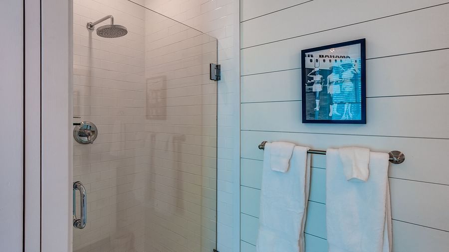 Bathroom with a glass shower enclosure, white towels, and framed wall art | Abaco Inn