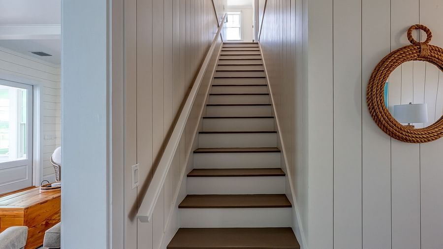Wooden staircase with white walls and a round mirror on the side | Abaco Inn