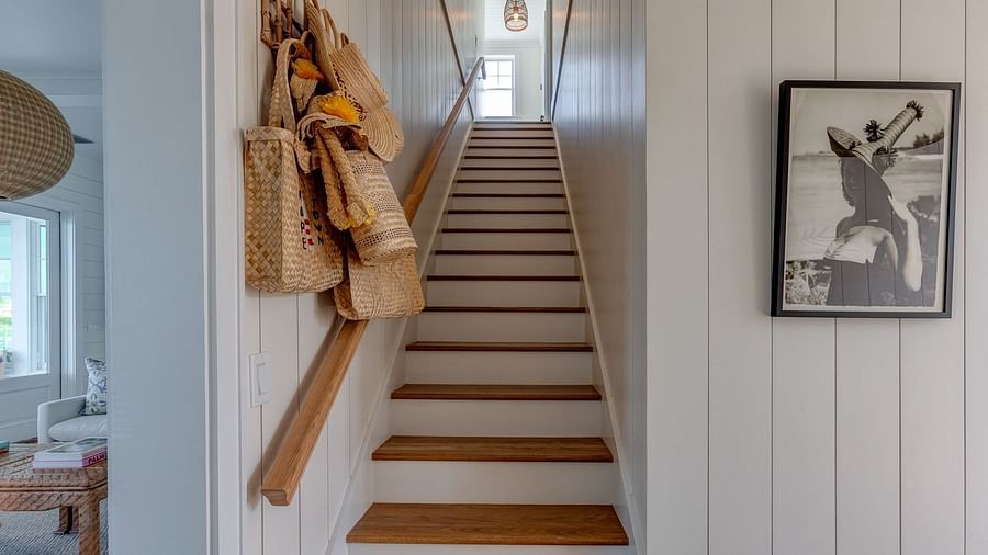 Wooden staircase with framed artwork and decorative hanging items | Abaco Inn
