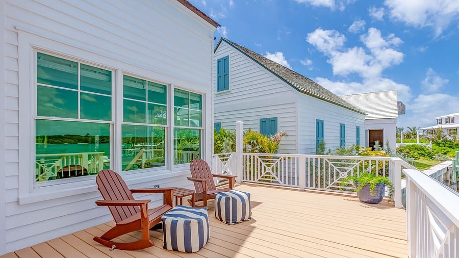 Wooden deck with Adirondack chairs outside a white coastal-style building with green shutters | Abaco Inn