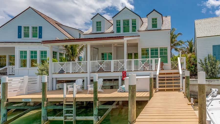 Waterfront villa with a private dock extending over turquoise waters under a blue sky | Abaco Inn