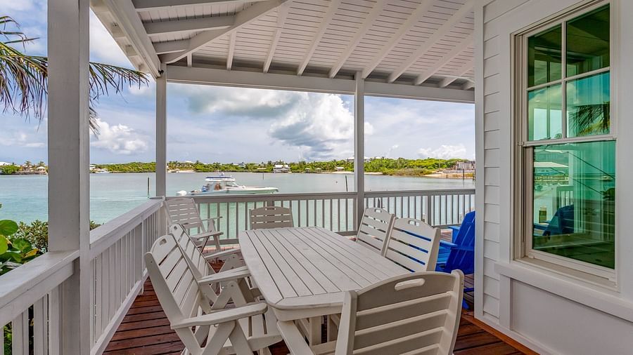 Spacious deck with a dining table and lounge chairs overlooking the water | Abaco Inn