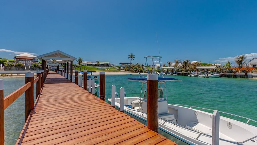 Wooden dock leading to the water with boats tied alongside | Abaco Inn