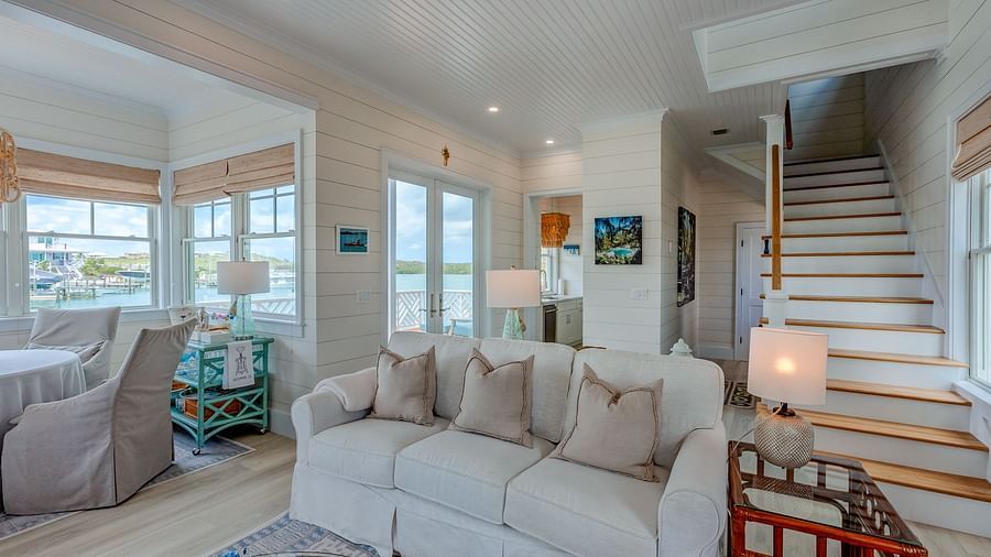 Living room with a large sectional sofa, chairs, and a staircase | Abaco Inn