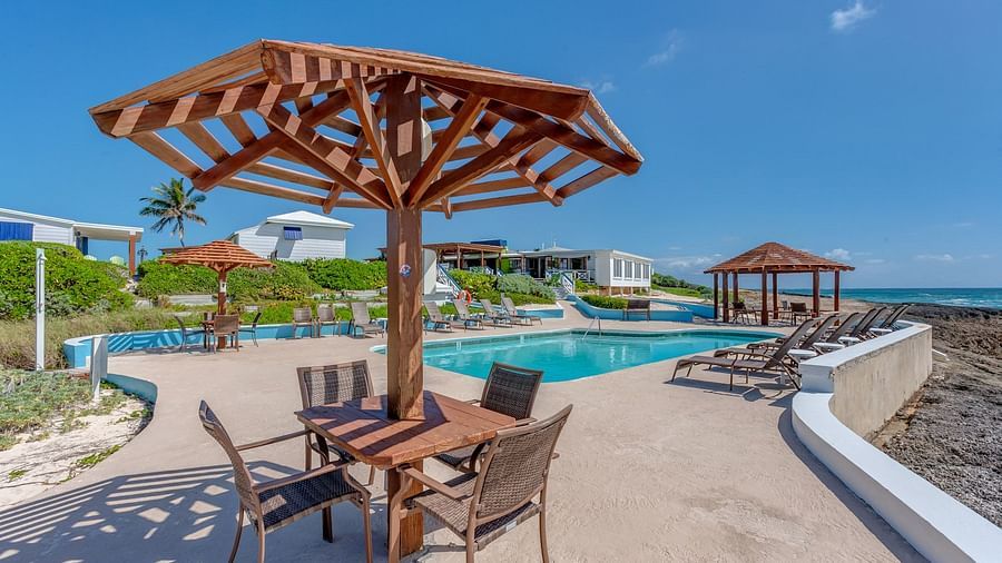 Poolside area with shade structure and ocean in the background | Abaco Inn