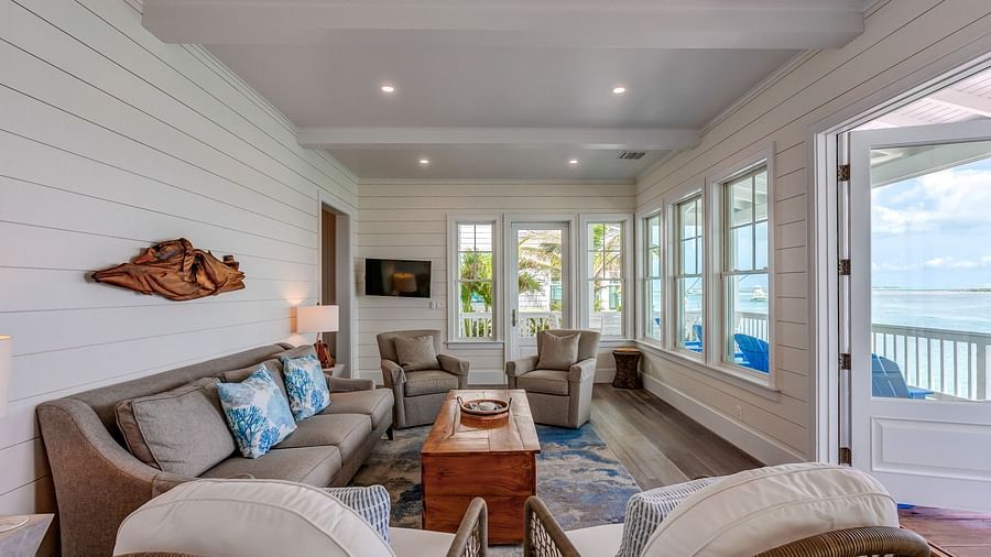 Living room with wicker chairs, a wooden coffee table, and large windows overlooking the water | Abaco Inn