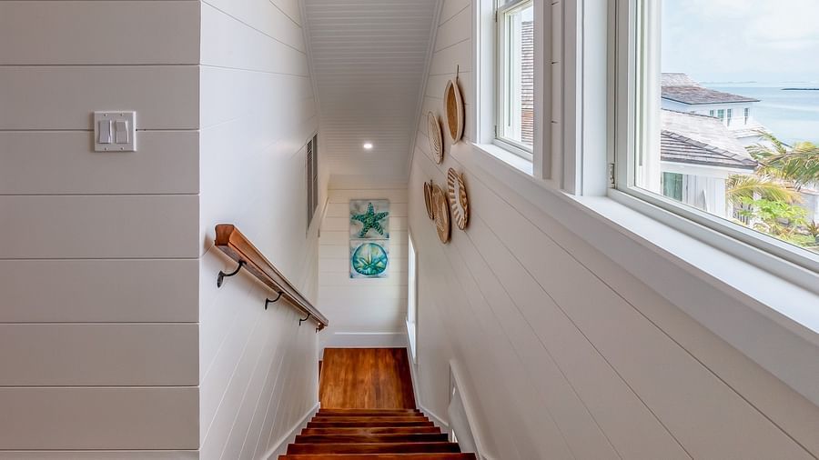 stairways at Abaco Inn with white walls, wall decors and windows with the sea view  .