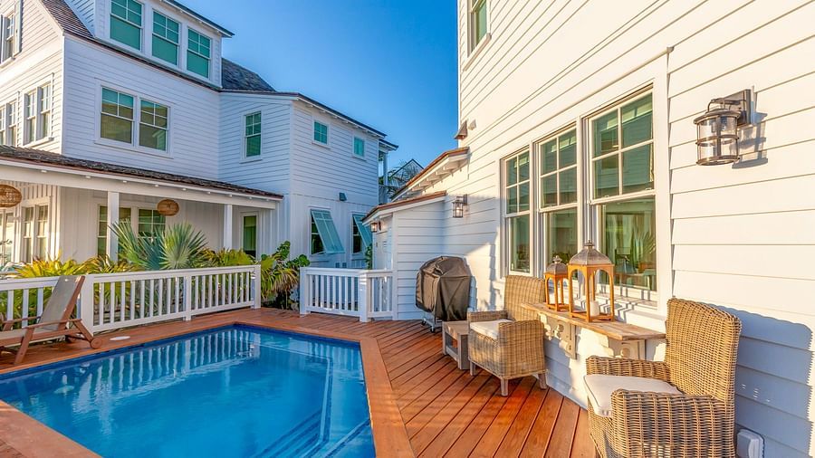 a swimming pool and two houses on a dock with wooden chairs at Abaco Inn.