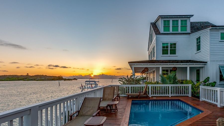 Swimming pool on a wooden dock with chairs, and the sea view with a sunset at Abaco Inn.