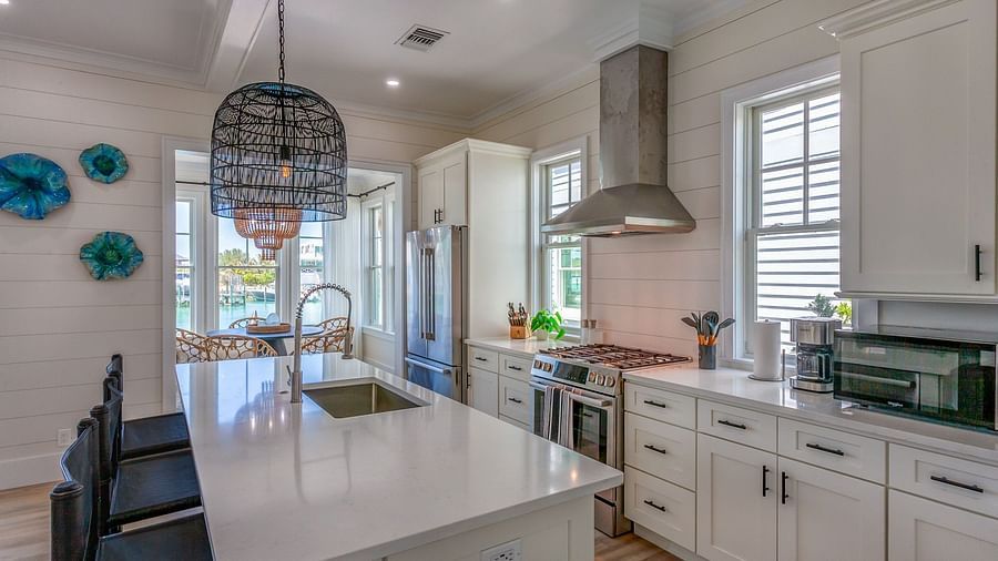 well lit Spacious kitchen with marble top table, chairs, cupboards, fridge, oven and a chimney at Abaco Inn.