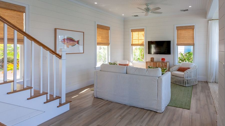 sitting area at abaco inn with sofa, TV, wall decors, and stairways.