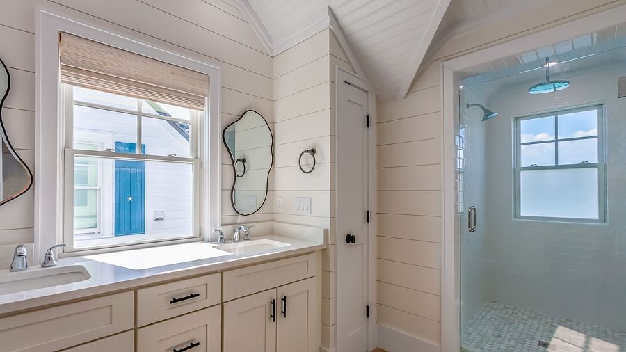 bathroom at abaco inn with cupboards, sinks, mirrors,  walk in shower, and windows .