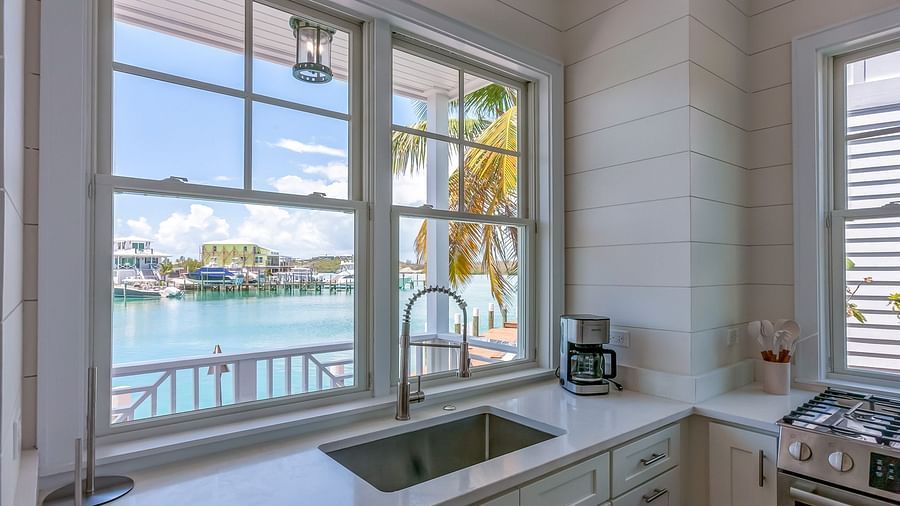 Bright and airy kitchen with a sink, cupboards, oven, and a window overlooking the sea at Abaco Inn.