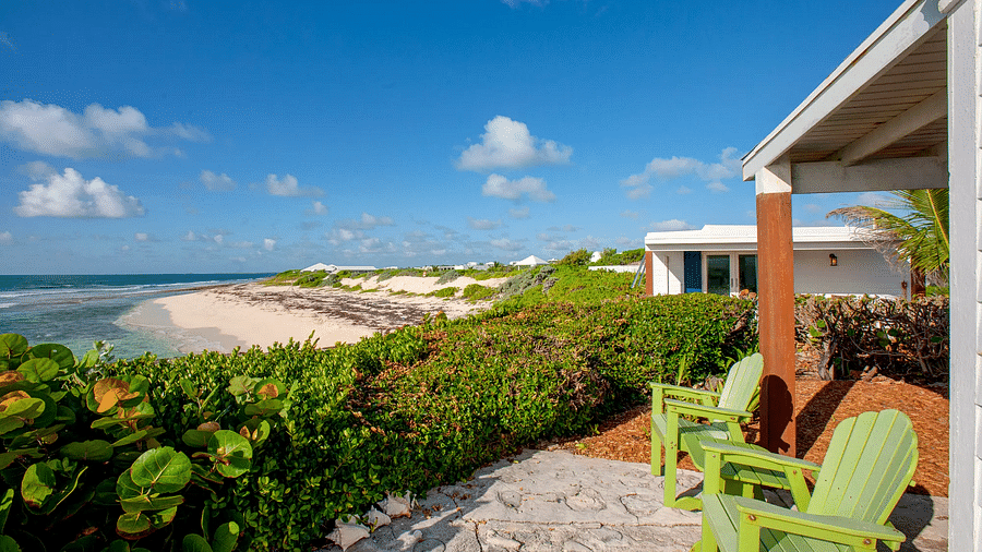 Patio with green chairs facing the ocean and coastal vegetation | Abaco Inn