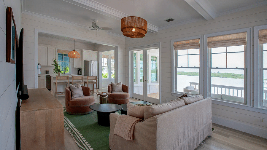 Living room with a beige sofa, green accents, and large windows | Abaco Inn