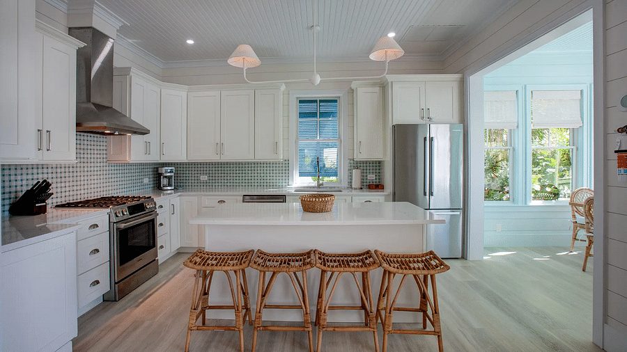 Modern kitchen with white cabinets, island seating, and pendant lights | Abaco Inn