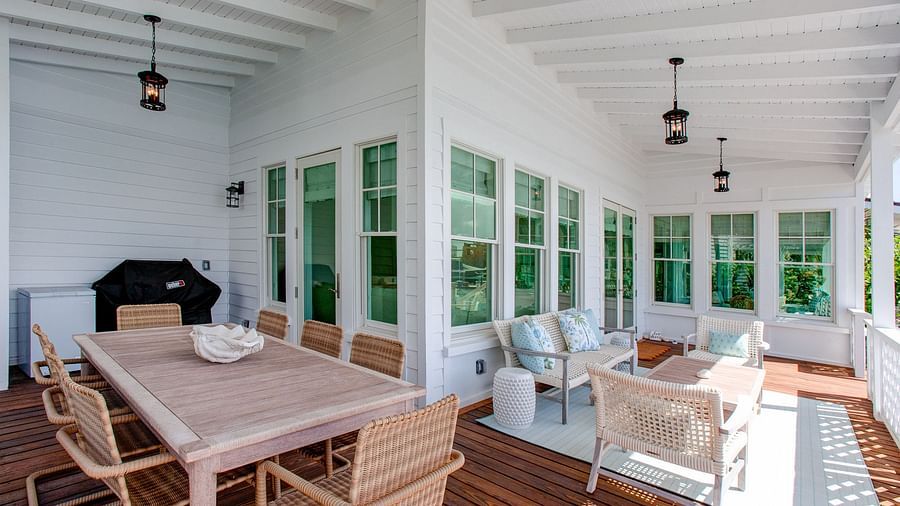 A spacious, sunlit room with extensive windows and light-toned walls, featuring a wooden dining table and chairs, along with various comfortable seating arrangements - Abaco Inn
