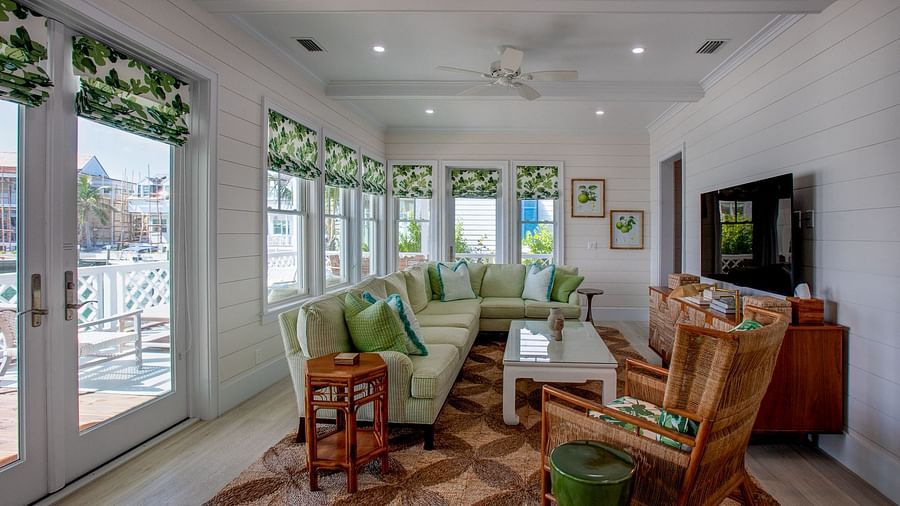 A spacious living room with multiple windows, comfortable seating arrangements, a television, and decorative elements throughout the well-lit space - Abaco Inn