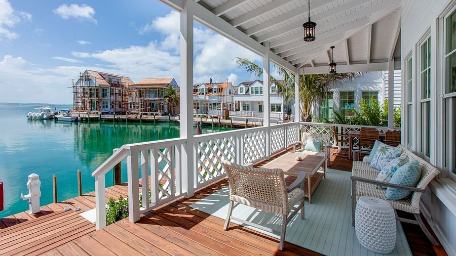 An expansive outdoor deck positioned over water, furnished with a dining table and various seating options, offering views of the surrounding area - Abaco Inn