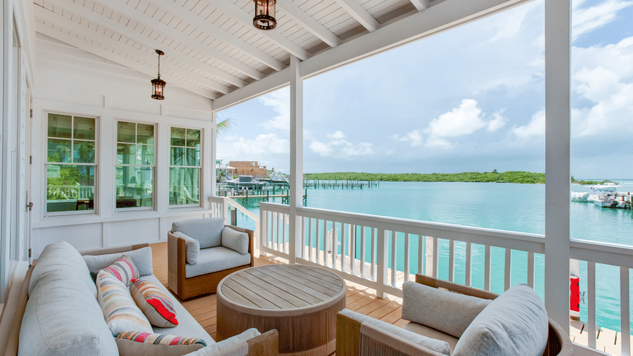 A balcony of Shoal Time Villa at Abaco Inn with cushioned seating, a small table, railing, and open views of the water.