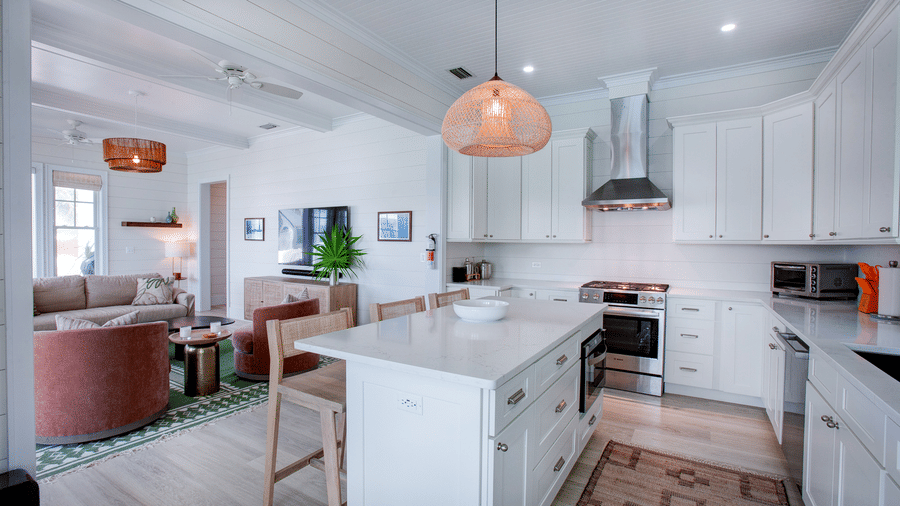 A wide kitchen view at Shoal Villa in Abaco Inn showing the island countertop, cooking area, pendant lights, and an open layout connecting to the living space.