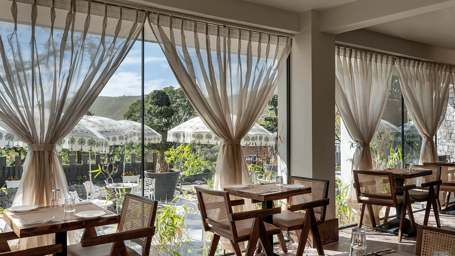 An inside view of a restaurant with chairs placed beside a glass window - The Samai, Bhimtal