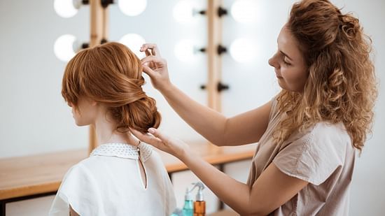 A female hairstylist arranging a woman's hair in a beautifully styled manner