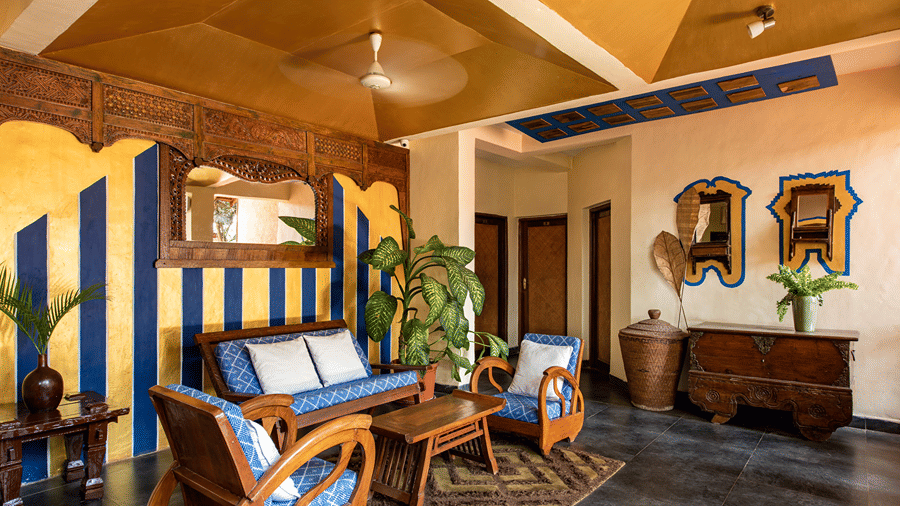Hotel lounge with wooden armchairs, blue cushions, framed mirrors and a warm timber ceiling.