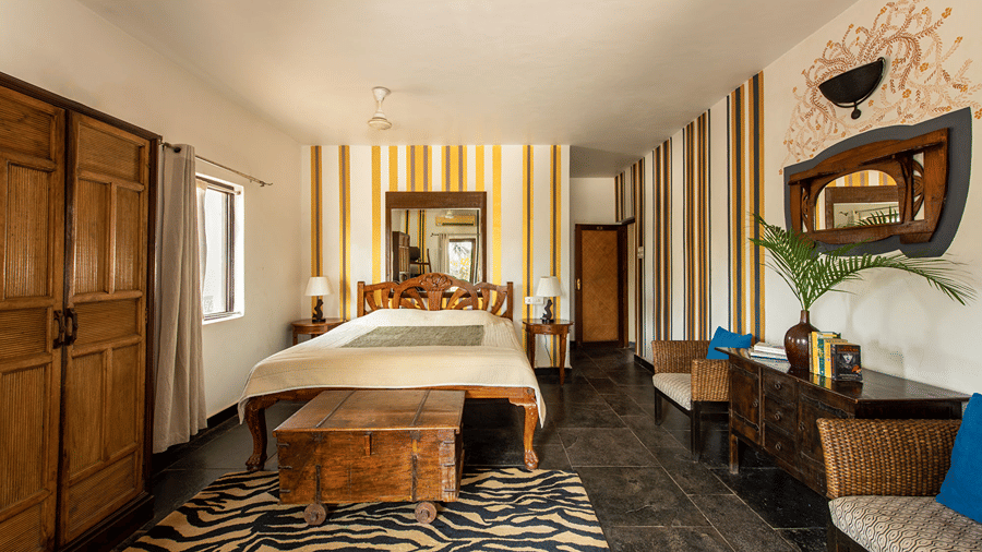 Spacious bedroom with a king size bed, wooden wardrobe, striped walls and a patterned rug.