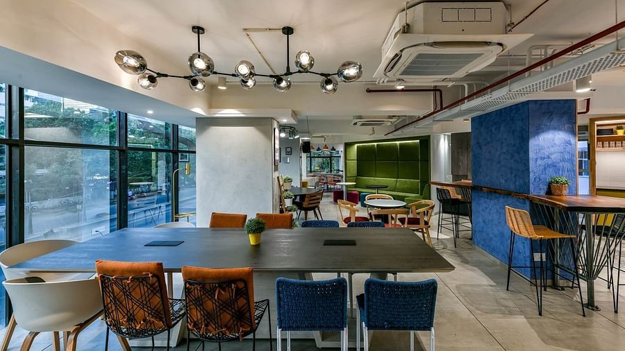 Shared workspaces with tables and chairs positioned across various sections of the area at Indie Stays, BKC Kalina.