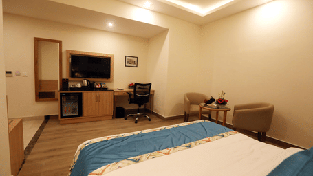 A well-appointed hotel room with a neatly made double bed and modern furniture.