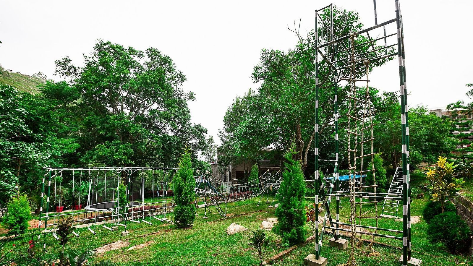 An image of the outdoor play area of Great Trails Yercaud by GRT Hotels featuring swings and other activities. 