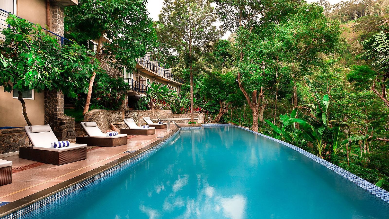 Image of the expansive swimming pool at our hotel along with chairs laid down at the side for relaxation at Great Trails Yercaud by GRT Hotels  