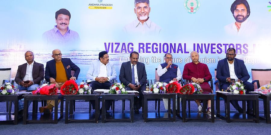 A panel of dignitaries seated on stage at the Vizag Regional Investors Meet, with a backdrop displaying Andhra Pradesh Tourism branding and images of key figures. 