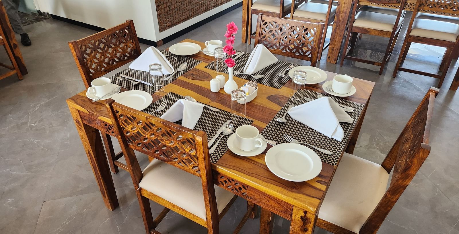 An indoor dining table set with plates and cutlery, ready for a meal at the Bamboo Saa Mulberry Resort, Pushkar.