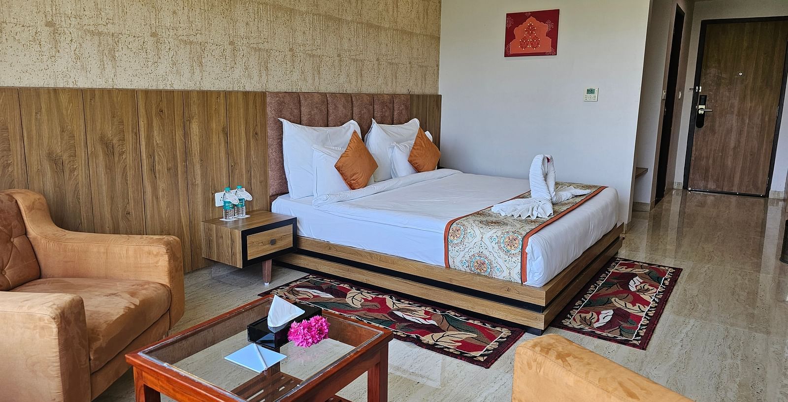 An interior shot of a hotel room at Bamboo Saa Mulberry Resort, with a bed, seating area, and a decorative rug.